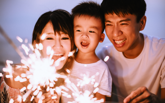 Man, woman and child looking at sparklers