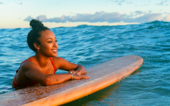 Girl in ocean leaning on her surfboard